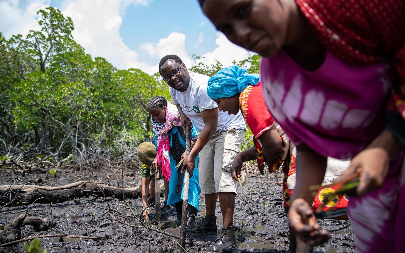Helping Hands TNC's George Maina plants mangrove seedlings with the Mtangawanda Women's Association, Lamu County, Kenya.
 © Roshni Lodhia