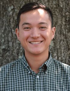 Headshot of Patrick Ma with a green collared shirt, a tree in the background.
