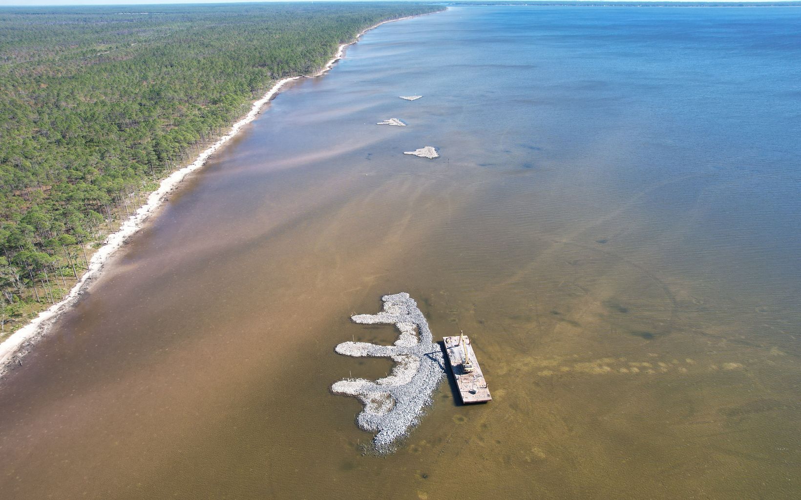 Newly constructed oyster reef with a barge sitting next to it.
