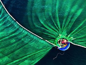 Um homem em um barco jogando uma rede