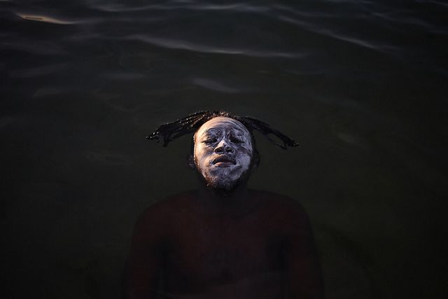 A young African refugee from the Democratic Republic of Congo floating in the waters of Guanabara Bay, Ramos Beach.