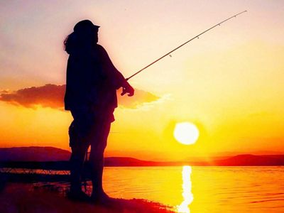 A person fishing in the sunset.