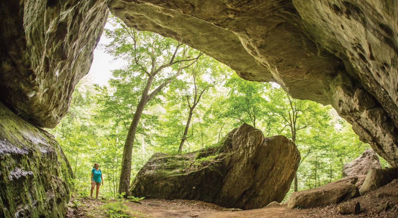 A hiker stands under Mantle Rock in Kentucky.