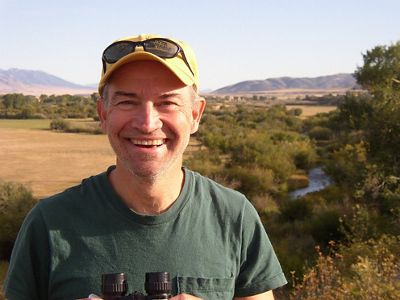 A man in a green shirt and hat smiling.