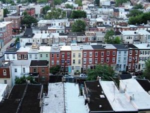 An urban landscape of rooftops and row houses.