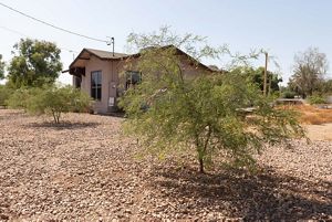 After: the same house with new trees and gravel.