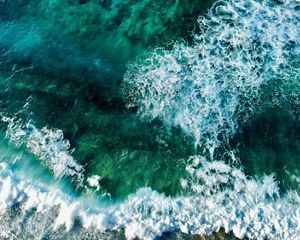 Aerial view looking straight down on waves breaking in a green ocean.