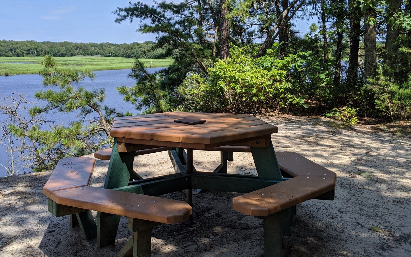 A picnic table sits next to a river and wetlands.