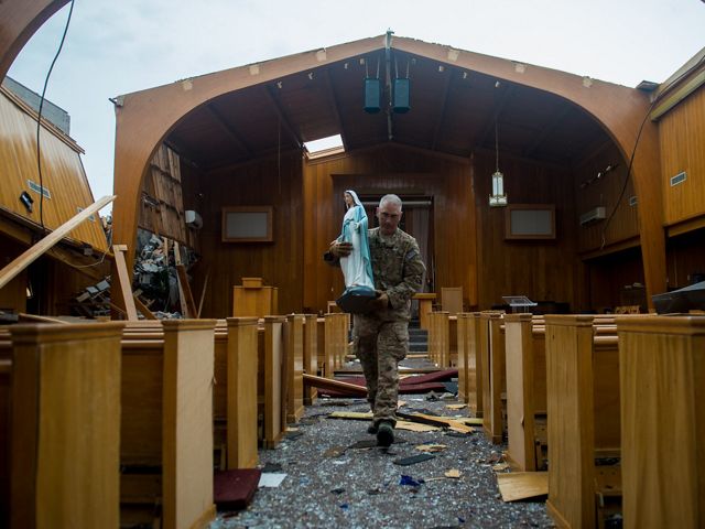 A chaplain carries a statue from the chapel at Tyndall Air Force Base after Hurricane Michael caused catastrophic damage to the base and surrounding area. 