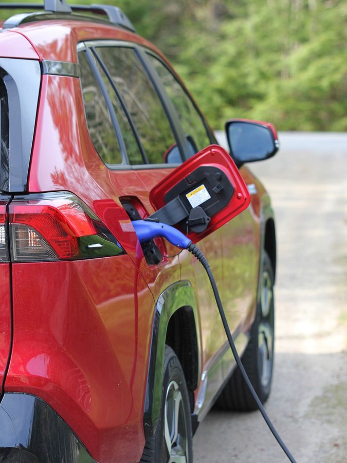 A charging unit is plugged into a red car.