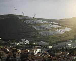 Wind and solar installations dot the hills overlooking a town in Portugal at sunset