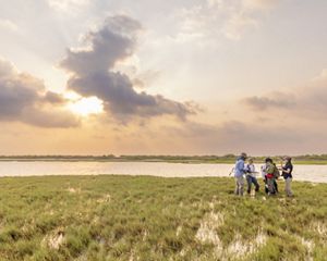 Five people stand together near an expanse of wetlands and water.