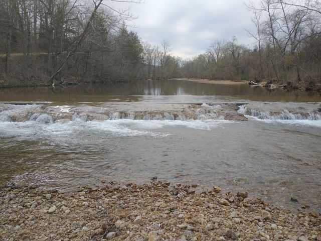 A low water crossing that is overflowing with water from a stream.