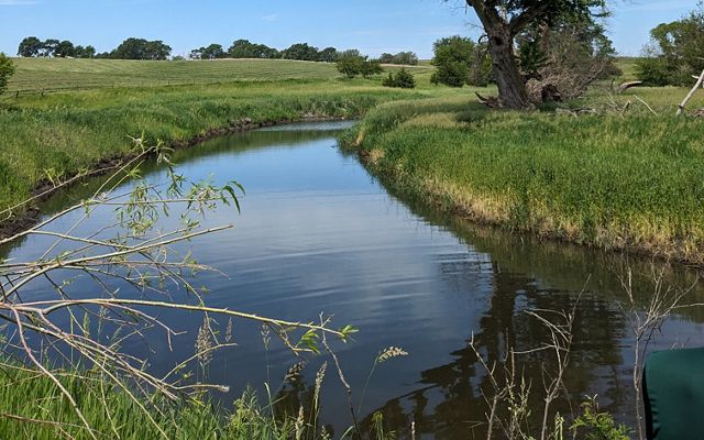 a calm river running through grassy fields.
