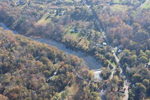 Autumn trees surrounding a river with a dam.