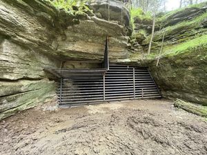 An gated entrance to a cave is built into large rock.