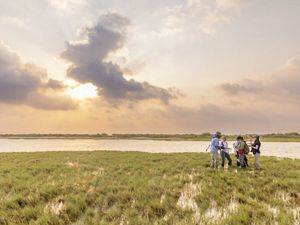 Fiver people stand together near an expanse of wetlands and water.