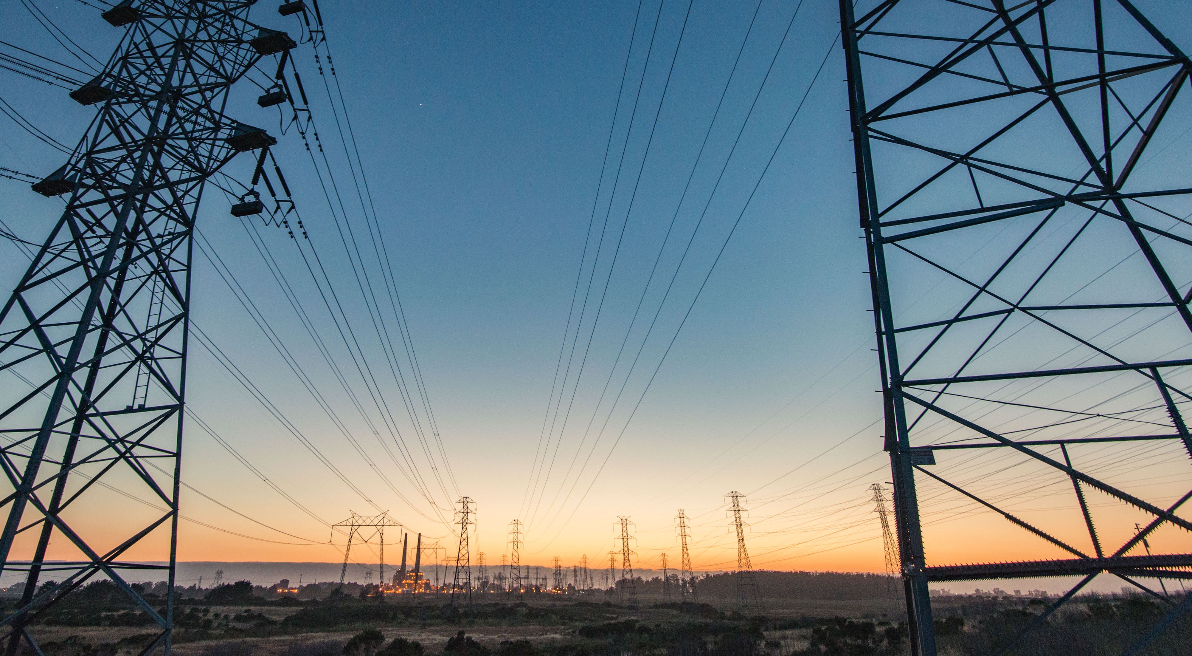 A photo of electrical transmission lines to the horizon at sunset.