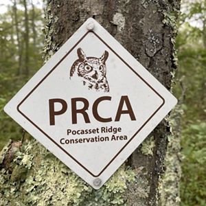 A white, diamond-shaped trail marker with a sketch of a great horned owl and the letters PRCA