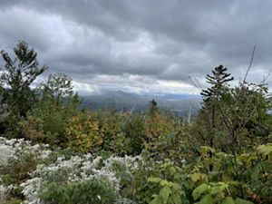 A view of mountains in the distance with sunrays coming through the clouds.