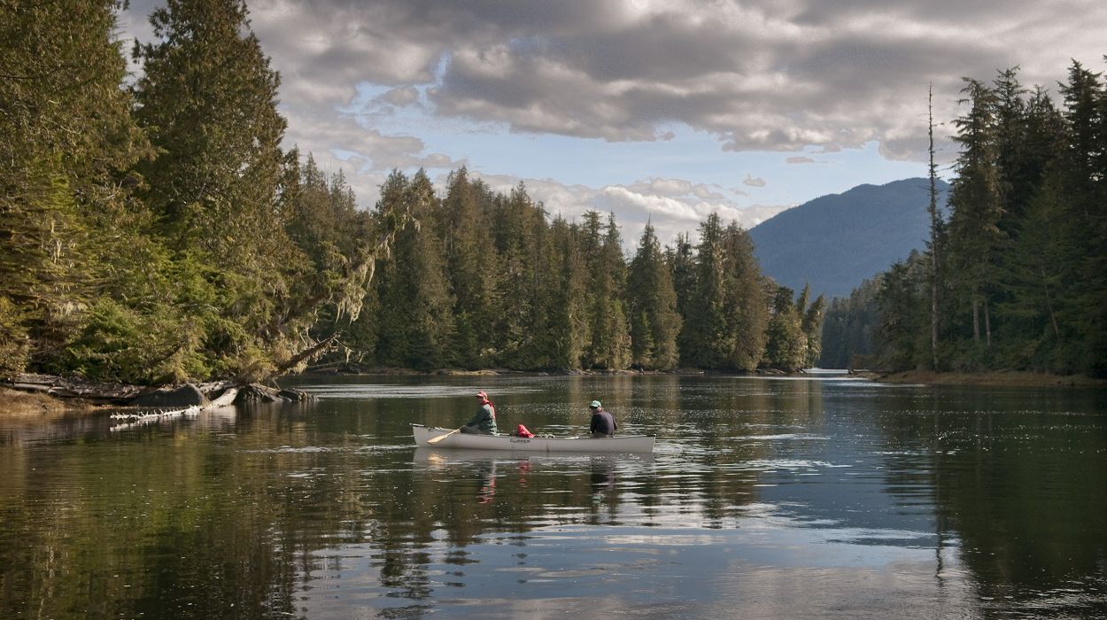 Two people canoeing on a river.