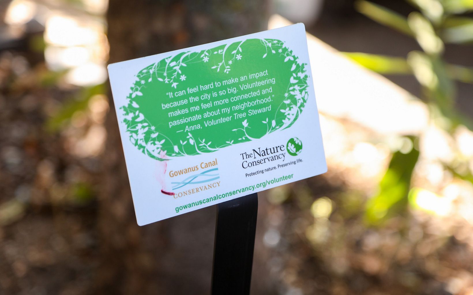 A closeup of a sign with a volunteer tree steward quote with the logos of The Nature Conservancy and Gowanus Canal Conservancy in view.