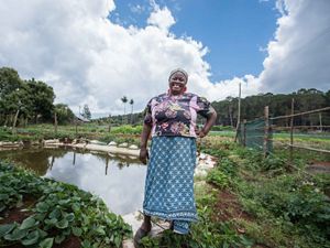 A farmer stands in front of her rainwater harvesting pan.