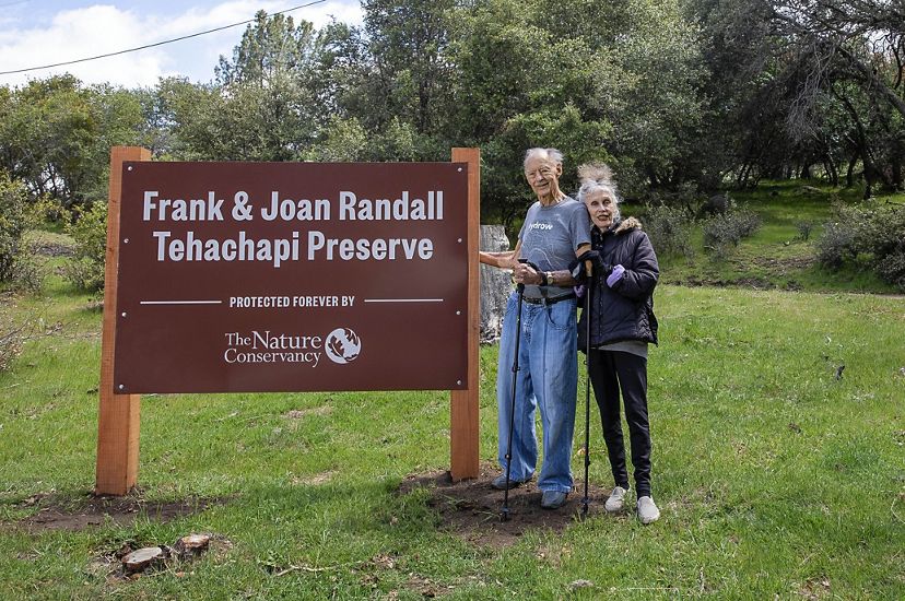 Frank and Joan Randall pose next to a sign bearing their names for the Tehachapi Preserve on Bear Mountain in Keene, CA.