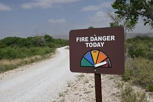 A sign before a road showing the fire danger and the arrow on EXTREME.
