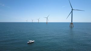 A wind farm in the ocean. White boat in the lower left corner looks small in comparison.