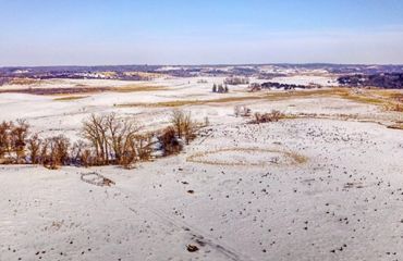 Aerial shot of grassland pastures covered in a thin layer of snow.