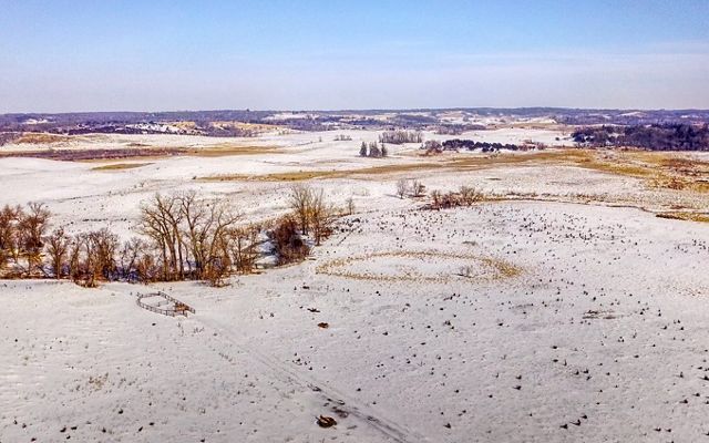 Aerial shot of grassland pastures covered in a thin layer of snow.
