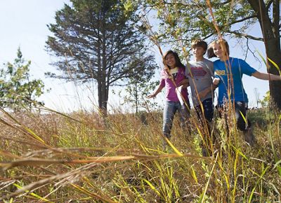 Three children exploring TNC's Nachusa Grasslands Preserve in Illinois under a sunny blue sky.