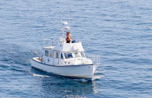 An aerial photo features a small white research boat surrounded by blue ocean