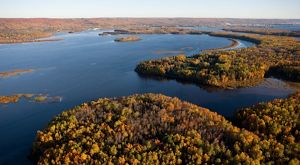 Aerial view of a broad river with islands in it covered in trees showing some fall colors.