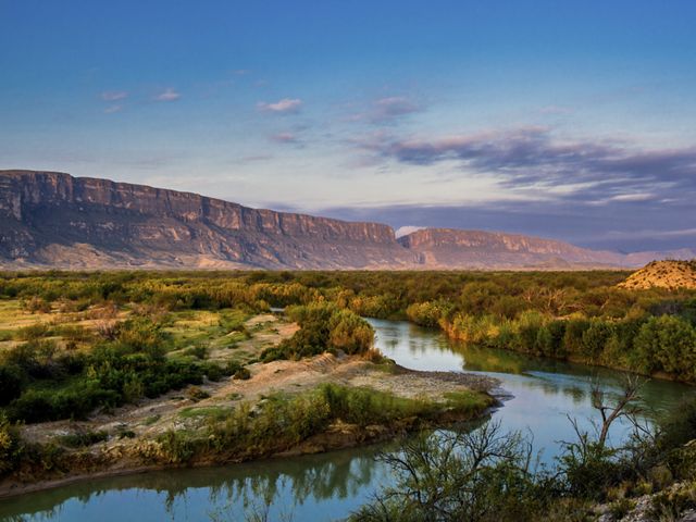A muddy brown river flows through towering mountains and rocky outcrops.