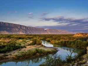 view of the rio grande and a canyon in the background against a sunset sky