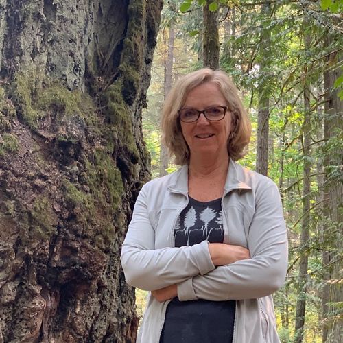 Person standing in the forest besides a tree.