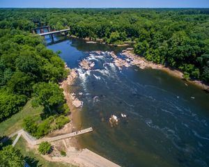 Aerial view of a rushing river surrounded by green forest.