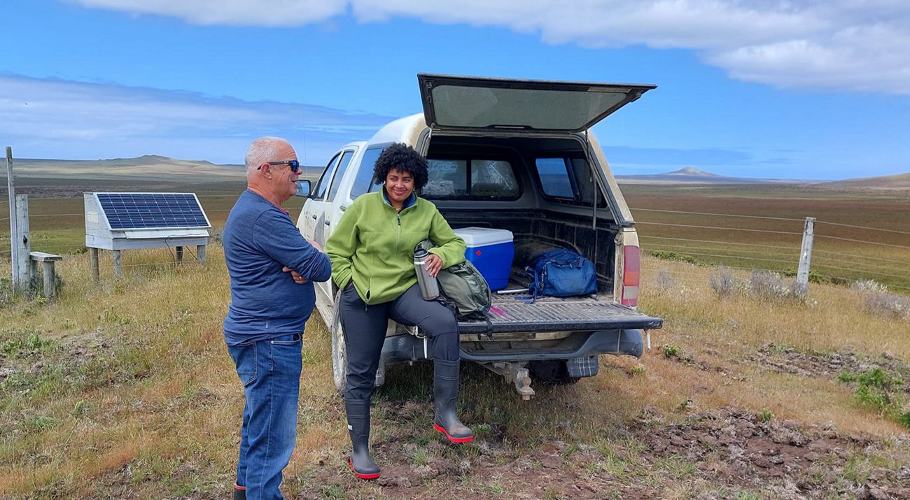 Rabia Shiekh sits on the tailgate of a pickup truck and talks to fellow researcher Rob Chappell.