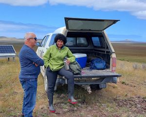 Rabia Shiekh sits on the tailgate of a pickup truck and talks to fellow researcher Rob Chappell.