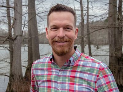 A man in a plaid shirt smiling at the camera.