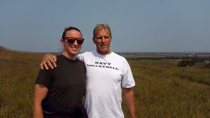 A young woman with her father who has his arm around her standing in wide open prairie.