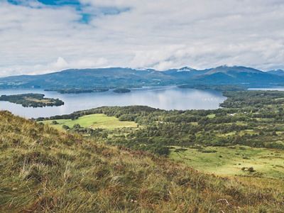 Background: mountains and lake; Foreground: rolling green hills
