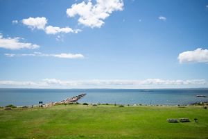 A grass lawn of a local state park meets up with ocean waters on a sunny day.