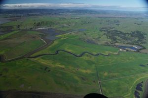 Aerial view of green lowlands near a bay.
