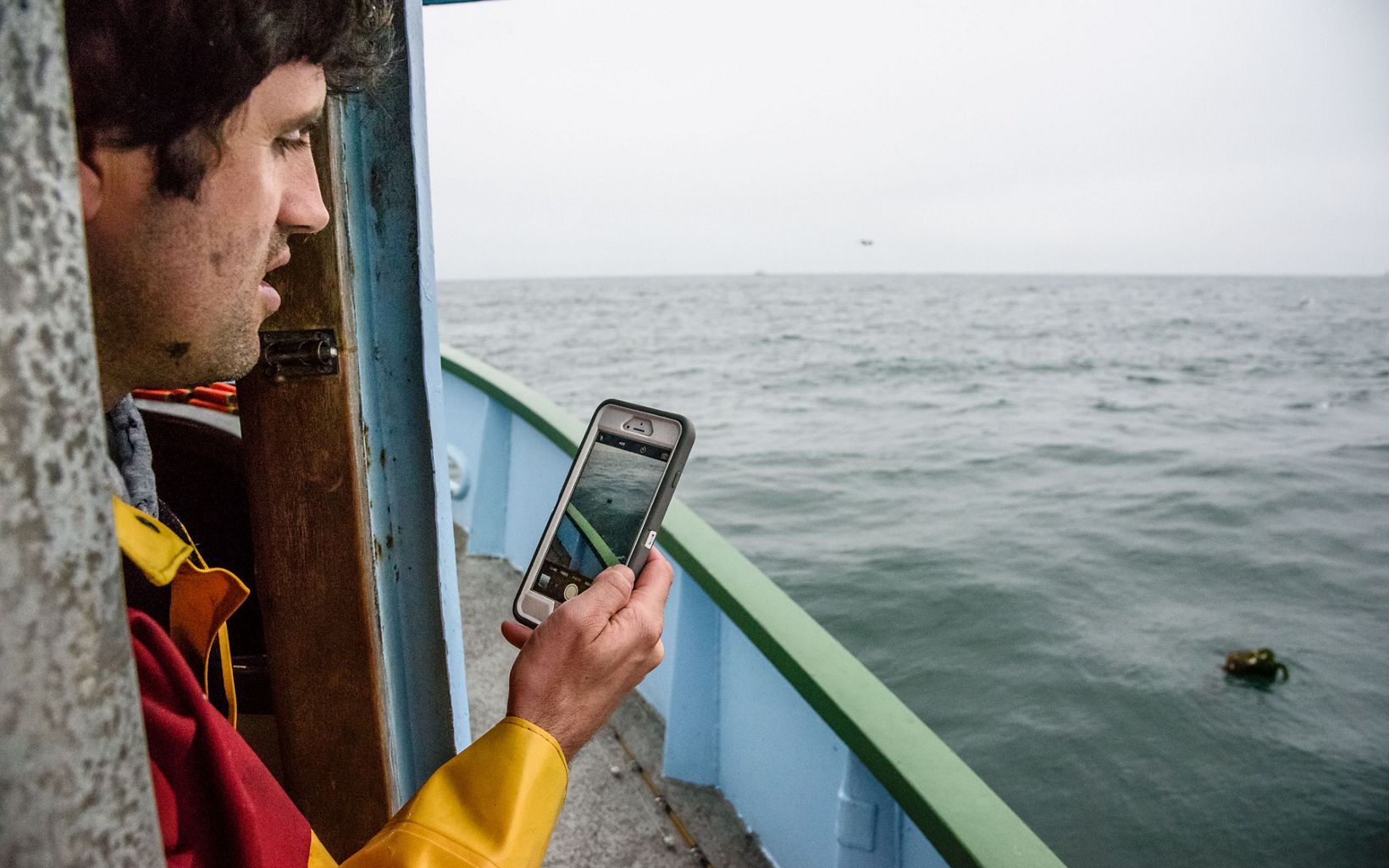 Un pescador toma una foto de los aparejos que flotan en el agua con su teléfono inteligente.