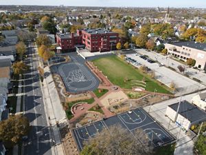 A brick school building with flourishing green spaces in place of the former concrete area.