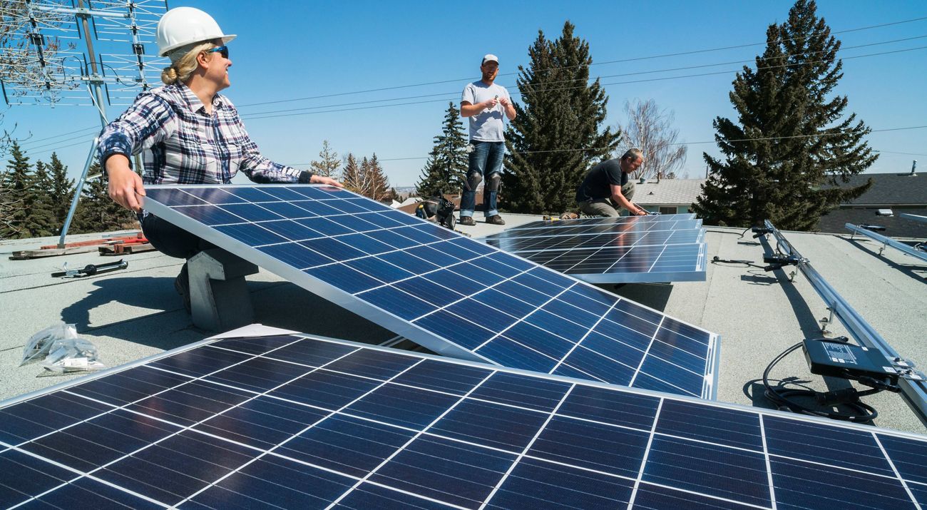 Workers install solar panels on a roof.
