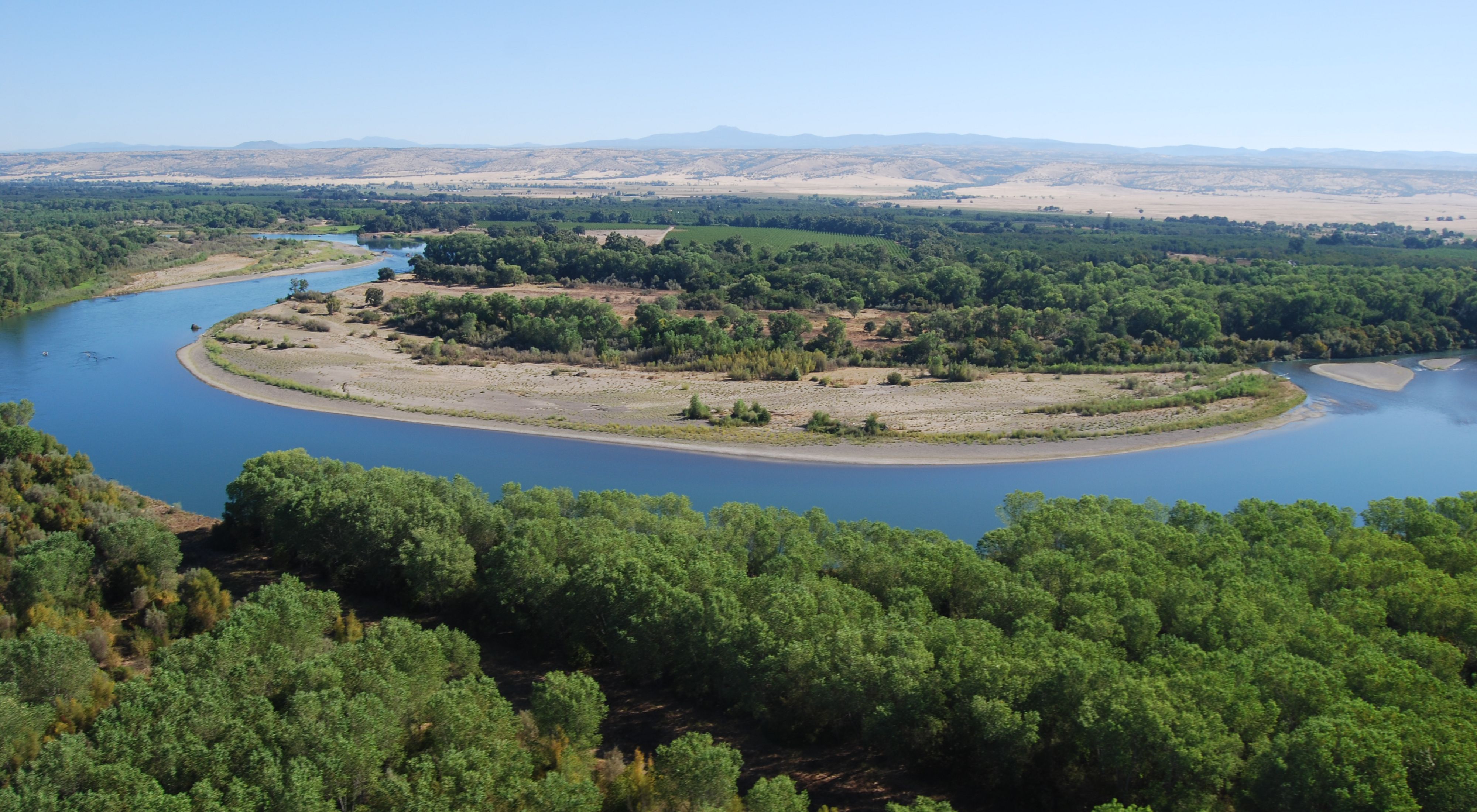 An aerial view of the Sacramento river in Tehama County with trees along each side. 
